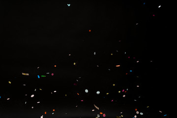 colorful party confetti flying in front of black