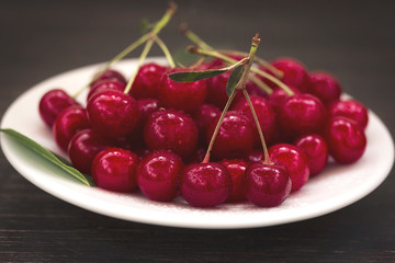 Ripe cherry on a white plate close-up