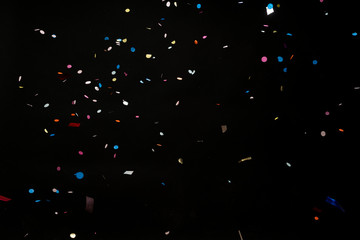 colorful party confetti flying in front of black