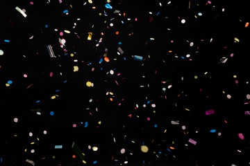 colorful party confetti flying in front of black