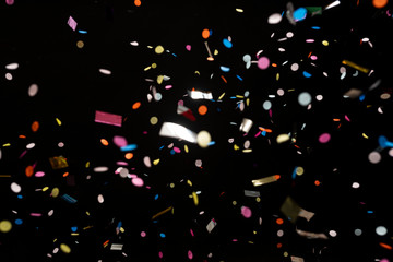 colorful party confetti flying in front of black