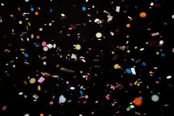 colorful party confetti flying in front of black