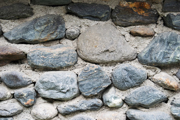 a fragment of stone wall lined with cobblestones background texture