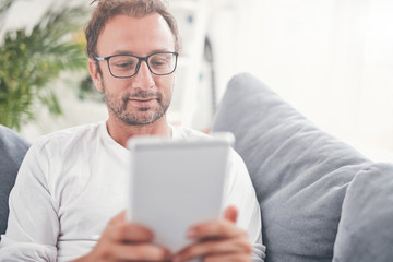 Man using tablet and sufring on the internet in his living room.