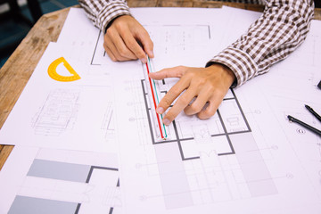 Fototapeta na wymiar Close-up hand of male Architect drawing blueprint on work space in construction site.