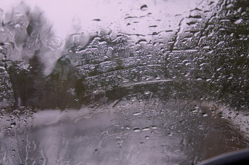 Car glass splattered with raindrops on the background of gray cloudy landscape, close-up, copy space, blur. instagram.