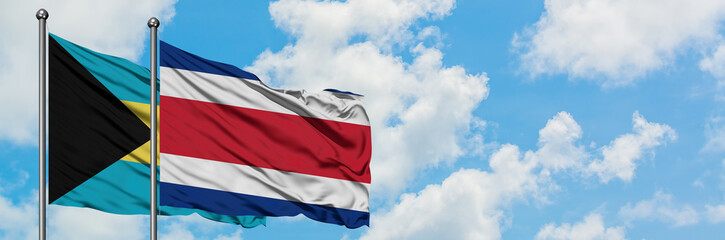 Fototapeta premium Bahamas and Costa Rica flag waving in the wind against white cloudy blue sky together. Diplomacy concept, international relations.