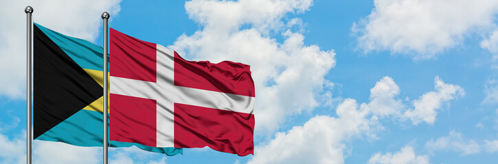 Bahamas and Denmark flag waving in the wind against white cloudy blue sky together. Diplomacy concept, international relations.
