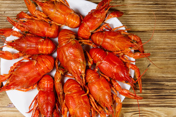 Boiled crayfish in plate on wooden table. Top view