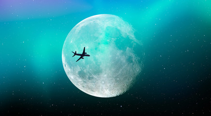 Passenger airplane in the sky against blue full moon and aurora borealis "Elements of this image furnished by NASA "