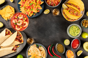 Mexican food, many dishes of the cuisine of Mexico, flat lay, shot from the top on a black background, forming a frame for copy space. Nachos, tequila, guacamole etc