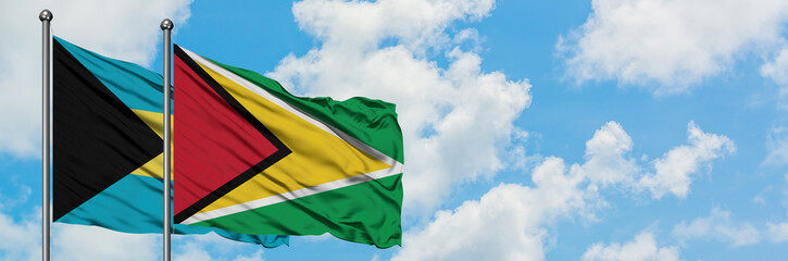 Fototapeta na wymiar Bahamas and Guyana flag waving in the wind against white cloudy blue sky together. Diplomacy concept, international relations.