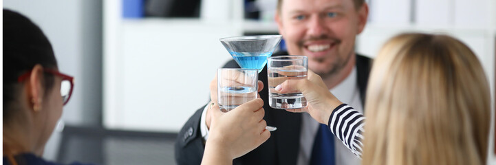 Portrait of joyful man in office drinking delicious blue cocktail in festive glass. Happy people...