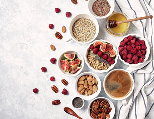 Healthy breakfast, top view. Oatmeal porridge with raspberries, figs, chia seeds, flax seeds, almonds and pecans, honey and coffee.