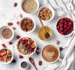Healthy breakfast, top view. Oatmeal porridge with raspberries, figs, chia seeds, flax seeds, almonds and pecans, honey and coffee.