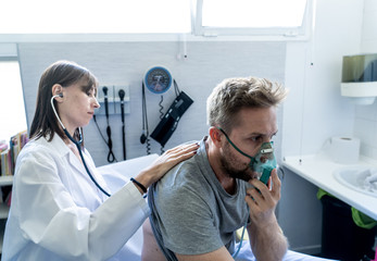 Sick man Inhaling Through Oxygen Mask having a medical exam by female doctor at hospital - obrazy, fototapety, plakaty