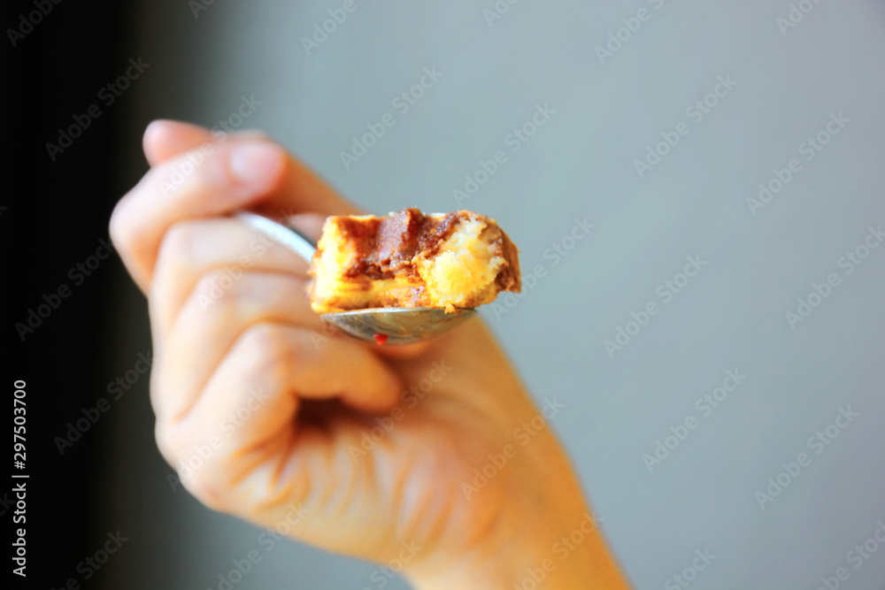 Wall mural chocolate waffles on a stainless steel spoon in a woman's hand