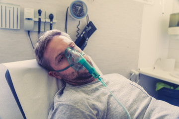 Sick man with oxygen mask in emergency room at hospital