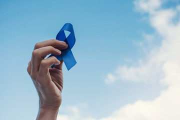 Man Hands holding blue ribbon over blue sky, Prostate Cancer Awareness, November blue, Movember Men...