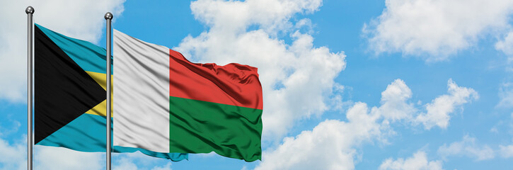Obraz premium Bahamas and Madagascar flag waving in the wind against white cloudy blue sky together. Diplomacy concept, international relations.