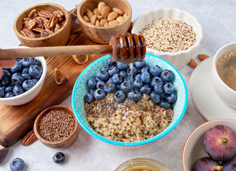healthy breakfast, quinoa porridge with blueberries, nuts, seeds and superfoods