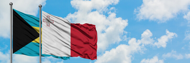 Naklejka premium Bahamas and Malta flag waving in the wind against white cloudy blue sky together. Diplomacy concept, international relations.