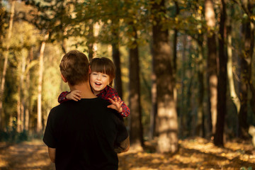 Father and his toddler son walking during the hiking activities in autumn forest at sunset