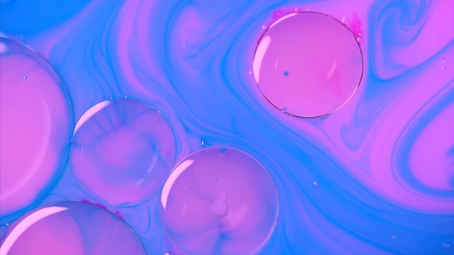 Clorful rgeous and vibrant background, cosmetic effect. Pink bbbles loat in blue paint. Mixing paint, oil and milk. Abstract colorful paint and slow motion. Bubble in liquid.