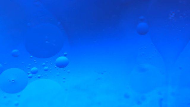 Psychedelic blue and yellow oil and water abstract background. Abstract colorful 4K video. Foam of Soap with Bubbles macro shot.Closeup bubbles in water. Oil drops on a water surface blue and yellow