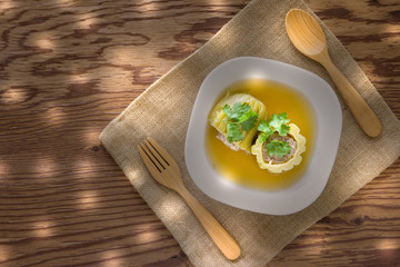 Stuffed bitter gourd soup with seasoned minced pork on wood background