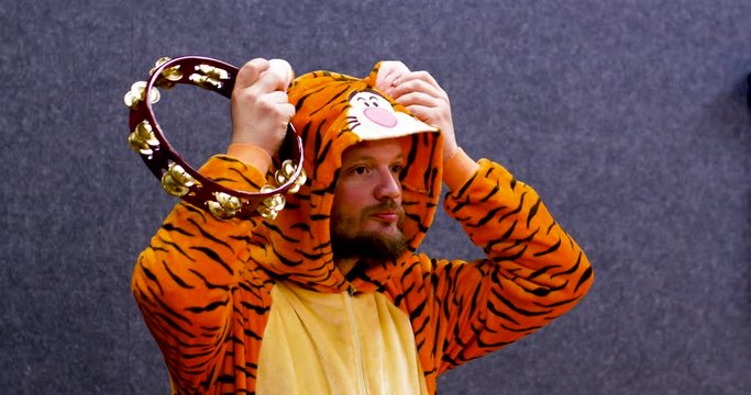 Man actor wearing a tiger clothe preparing his acting with a tambourine