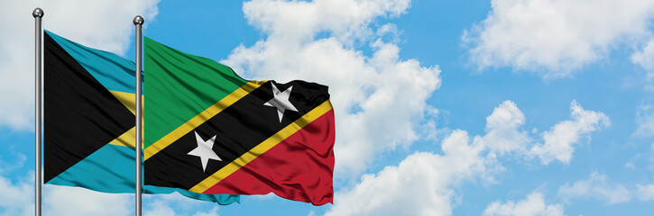 Bahamas and Saint Kitts And Nevis flag waving in the wind against white cloudy blue sky together. Diplomacy concept, international relations.
