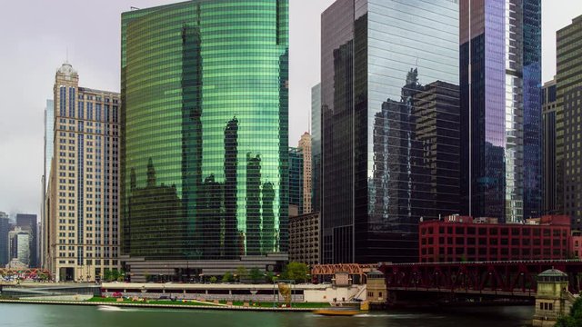 City of Chicago at Wolf Point. Time lapse of busy traffic on the street and the Chicago River with modern glass skyscrapers in the background.