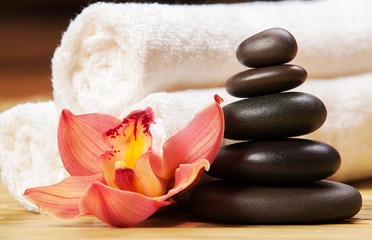 Fototapeta na wymiar Spa background. White towels on exotic plant, beautiful orchid flower and balancing stones for relax spa massage and body treatment. Asian medicine with aroma and stone therapy for beauty healthy body