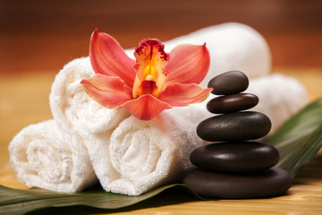Spa background. White towels on exotic plant, beautiful orchid flower and balancing stones for...
