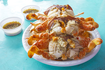 Steamed crabs with spicy sauce on blue desk
