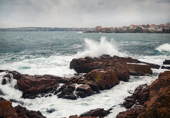 Sea waves crash on a rocky shore. Seascape in cloudy weather.