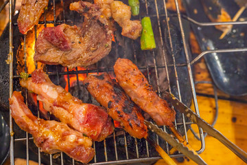 Closeup photo of grilling barbecue meat on flaming charcoal stove