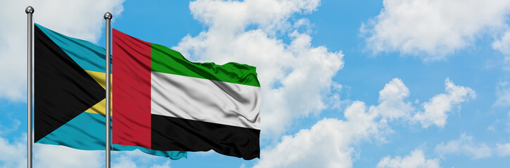Bahamas and United Arab Emirates flag waving in the wind against white cloudy blue sky together. Diplomacy concept, international relations.