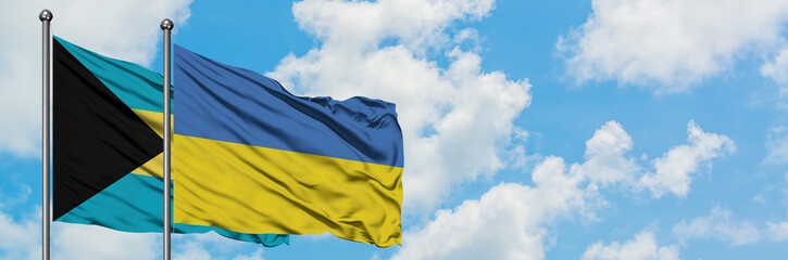 Bahamas and Ukraine flag waving in the wind against white cloudy blue sky together. Diplomacy concept, international relations.