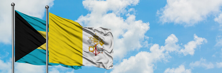 Bahamas and Vatican City flag waving in the wind against white cloudy blue sky together. Diplomacy concept, international relations.