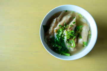 Shrimp wonton with braised pork in soup on wooden table / Select focus image