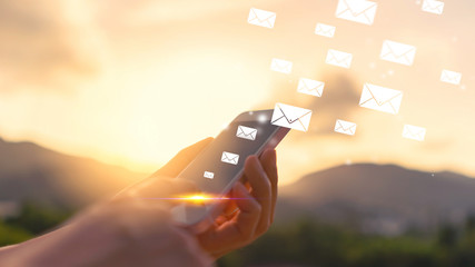 Woman hand using smart phone on top of mountain with email icon flying abstract background. Copy space technology business and travel nature holiday concept.