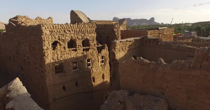 Green oasis in the desert terrain surrounded by clay and stones low rise houses. Monochromatic scenery somewhere in the Middle East.