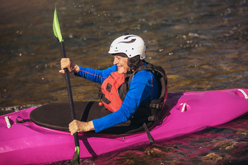 Active senior man paddling kayak. Gray hair man enjoy river kayaking.