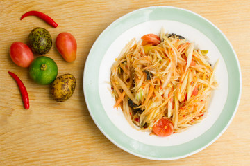 Papaya salad in a white plate on a wooden table , Space for text input