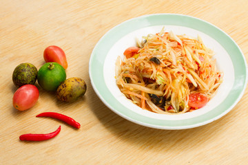 Papaya salad in a white plate on a wooden table , Space for text input
