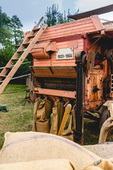 Historische Dreschmaschine in Betrieb. Auf dieser Seite wird das gedroschene Getreide in Jutesäcke abgefüllt. Im Vordergrund gefüllte Säcke