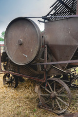 Fototapeta na wymiar Historische Strohpresse im Anschluss an eine Dreschmaschine in Betrieb. Das Rad dreht sich und zeigt Bewegungsunschärfe