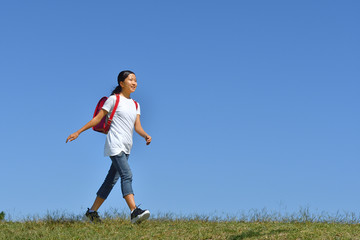 青空で歩く小学生の女の子（ランドセル）